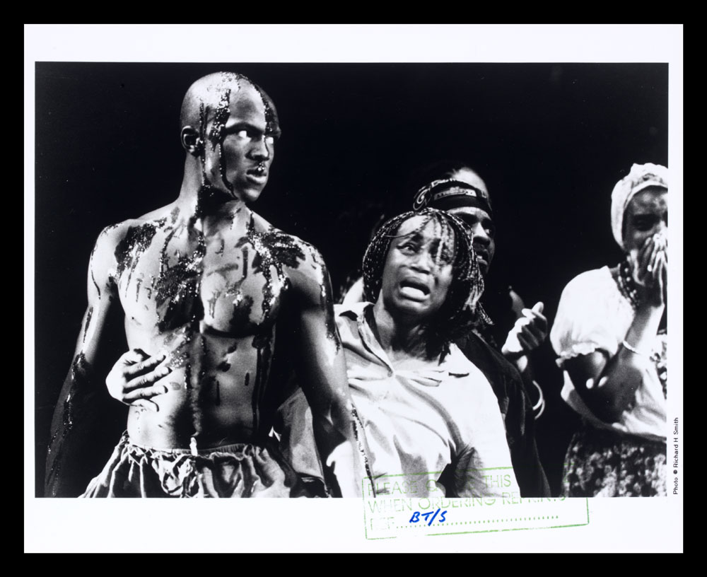 B&W photo of barechested man with crying woman from Zumbi