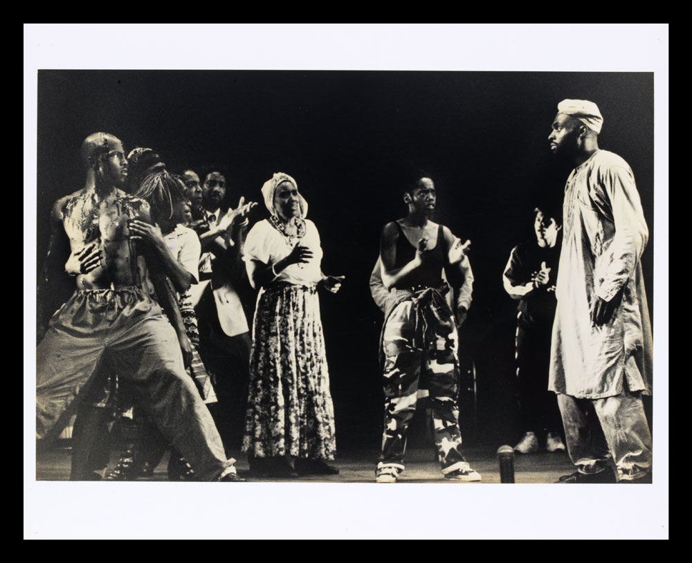 B&W photo of actors on stage, some clapping, from Zumbi