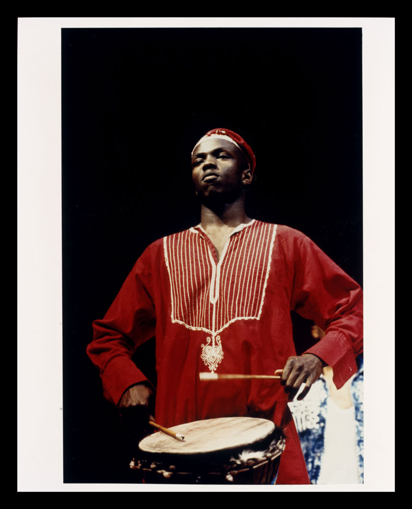 Colour photo of man wearing red with drum from Zumbi